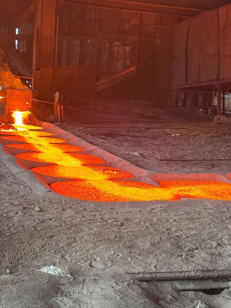 Molten alloy running from the tap into the sand runners of the casting bed