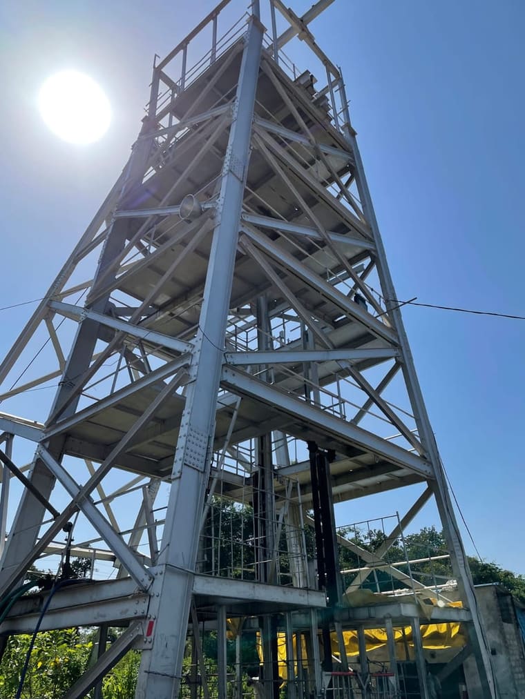 The steel headgear tower over the shaft at Ramrama, silhouetted against the sun